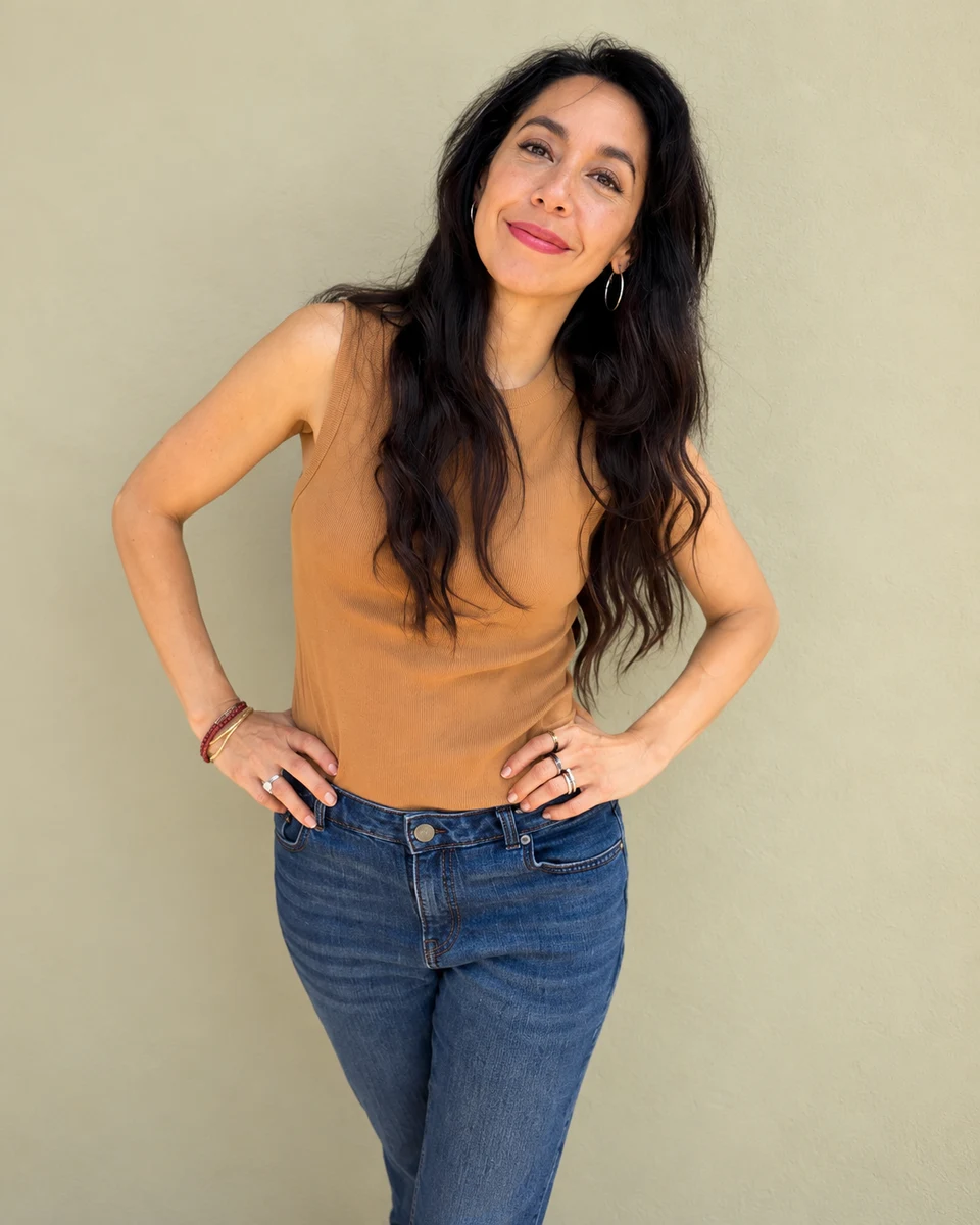 Jamie Seif smiling in an ochre top with her hands on her hips